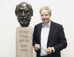 Einst und jetzt: Archivdirektor Gernot Peter Obersteiner mit der Büste des ersten Archivdirektors, Joseph von Zahn.