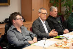 Gesprächsrunde am Konferenztisch. Eine Person spricht, daneben zwei weitere Personen. 