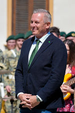 Bildbeschreibung: Ein Mann steht vor einer Gruppe Uniformierter.