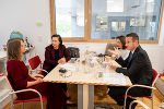 Vier Personen sitzen an einem Tisch und führen ein Gespräch.