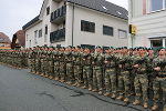 Soldaten stehen nebeneinander in einer Reihe vor einer Hausfassade.